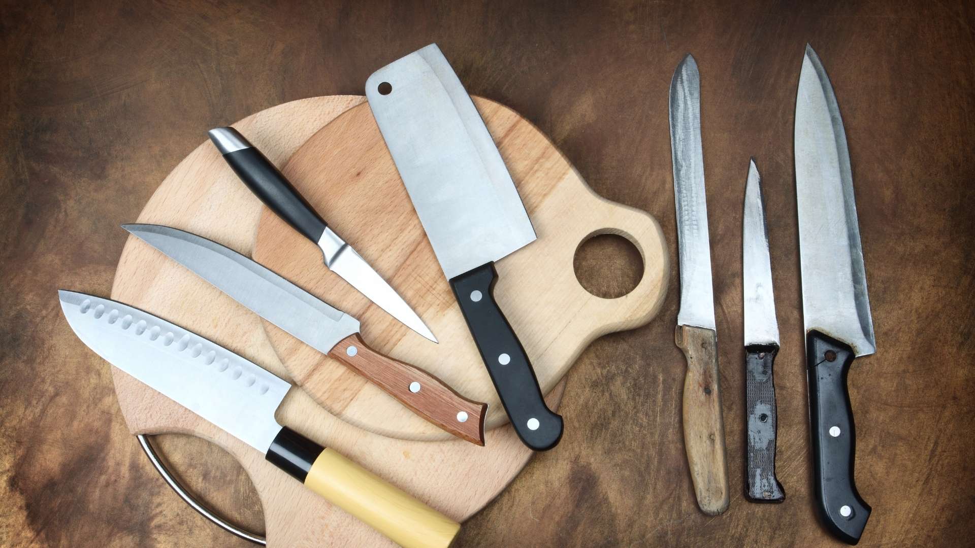 variety of knives placed on the table and cuttng board