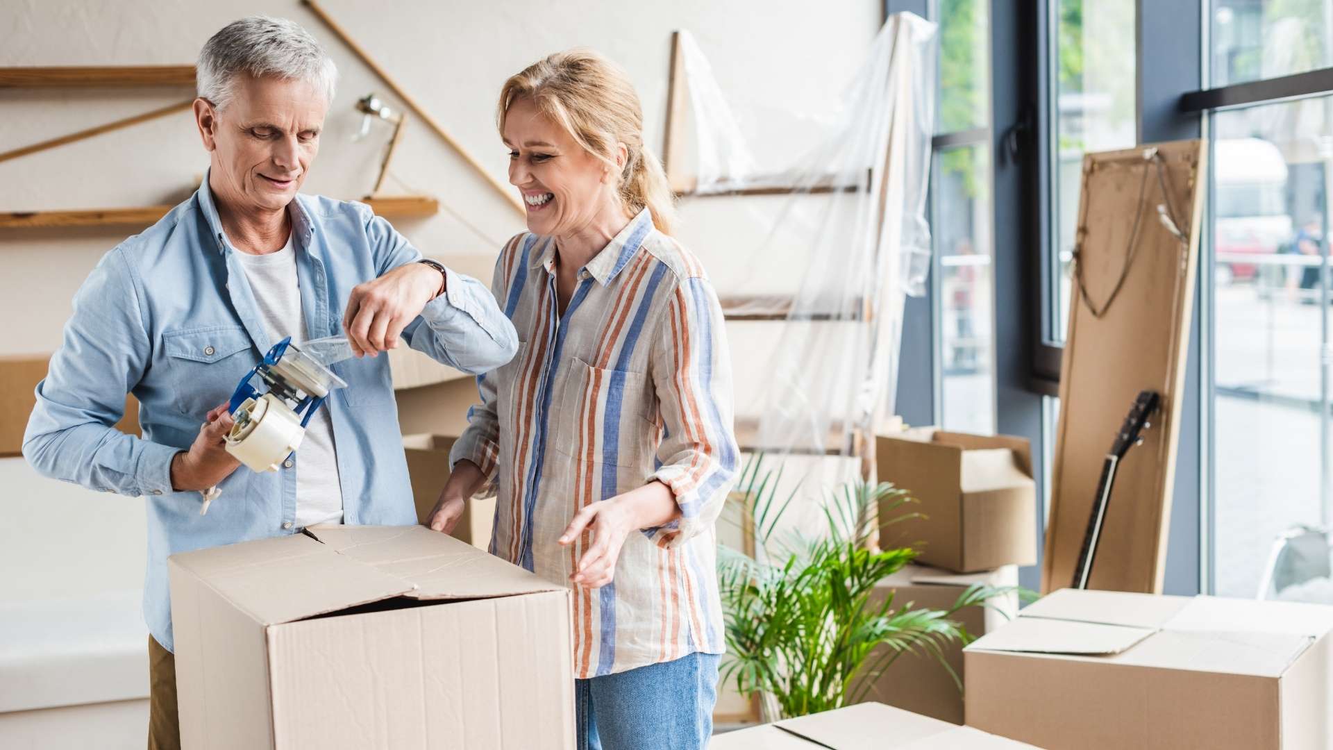 a senior couple taping and packing boxes