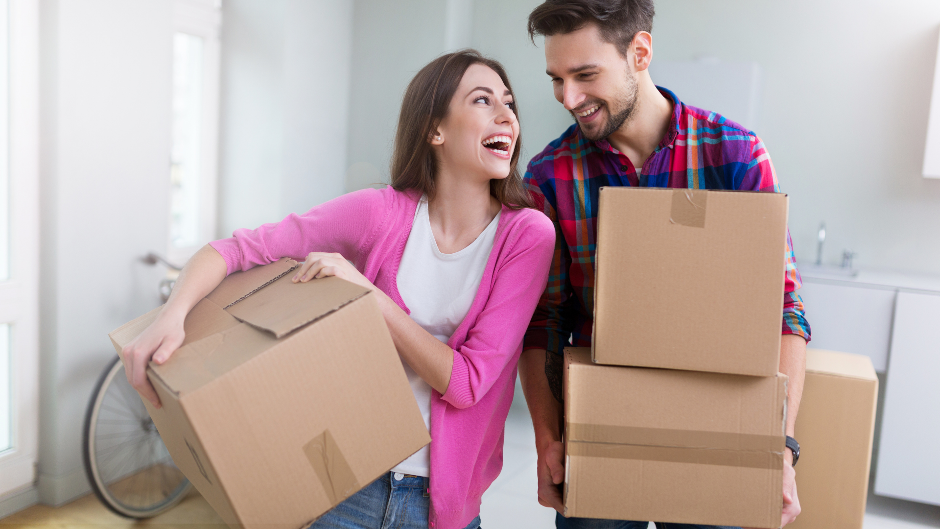 couple holding moving boxes in apartment