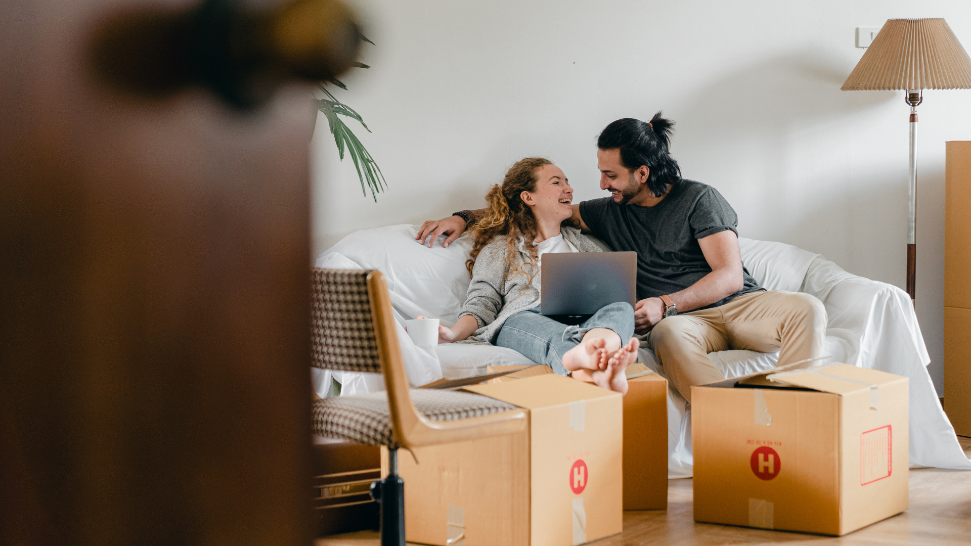 couple sitting on couch with moving boxes